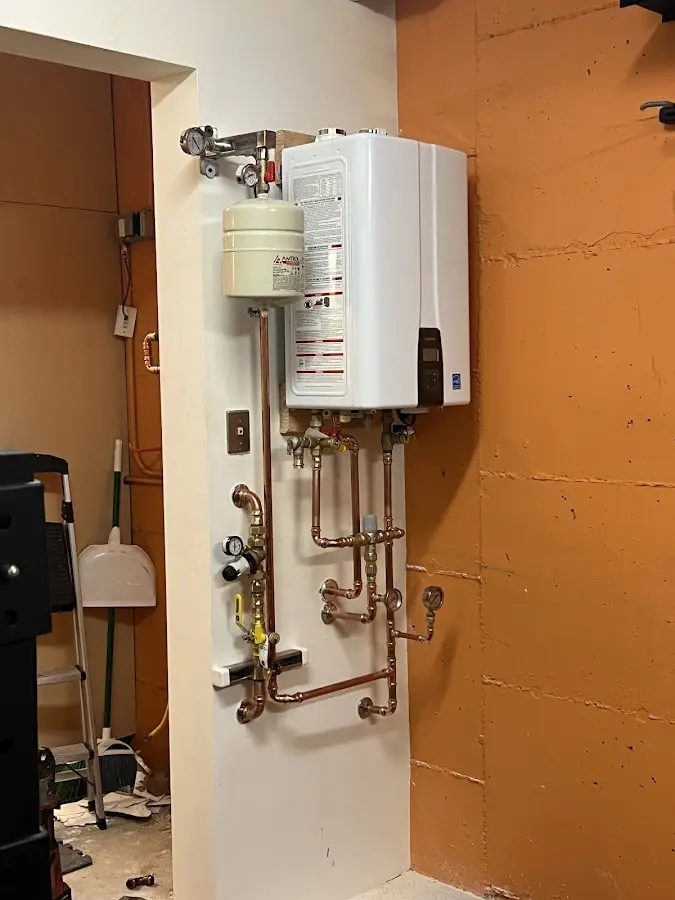 Plumbing technician inspecting water heater connections in East Earl